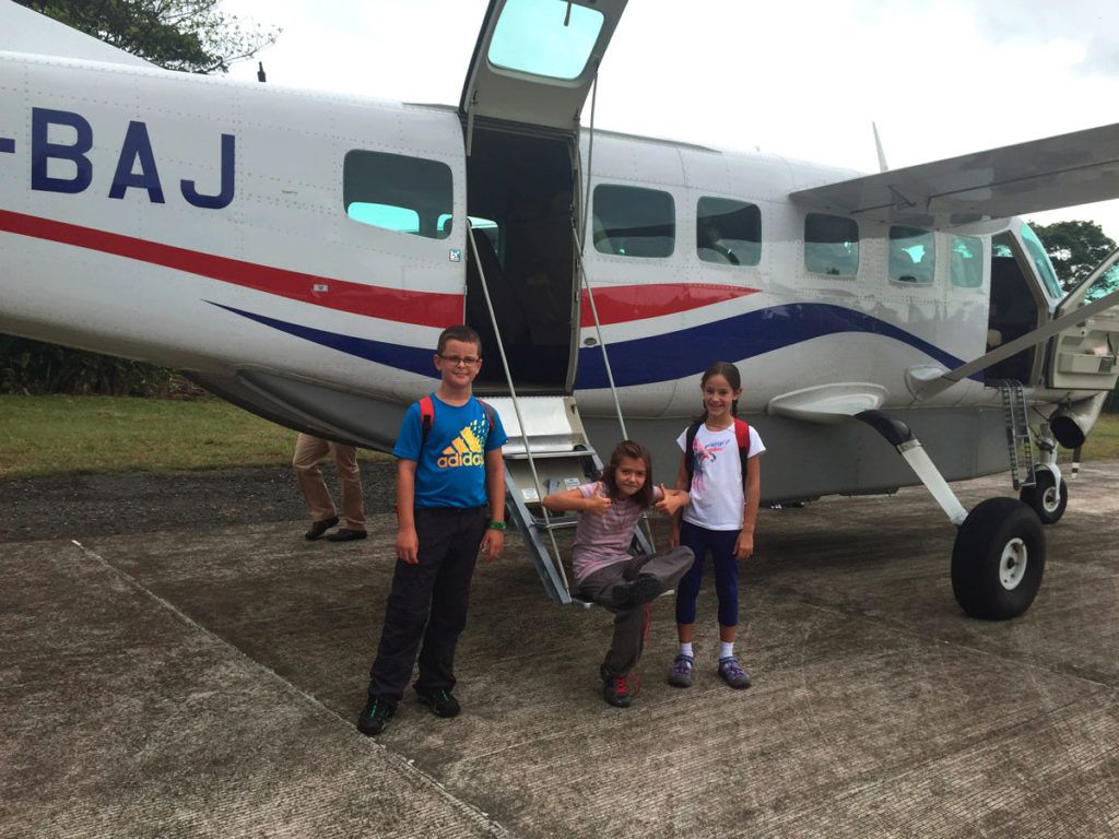 Tres niños frente a una avioneta en Costa Rica