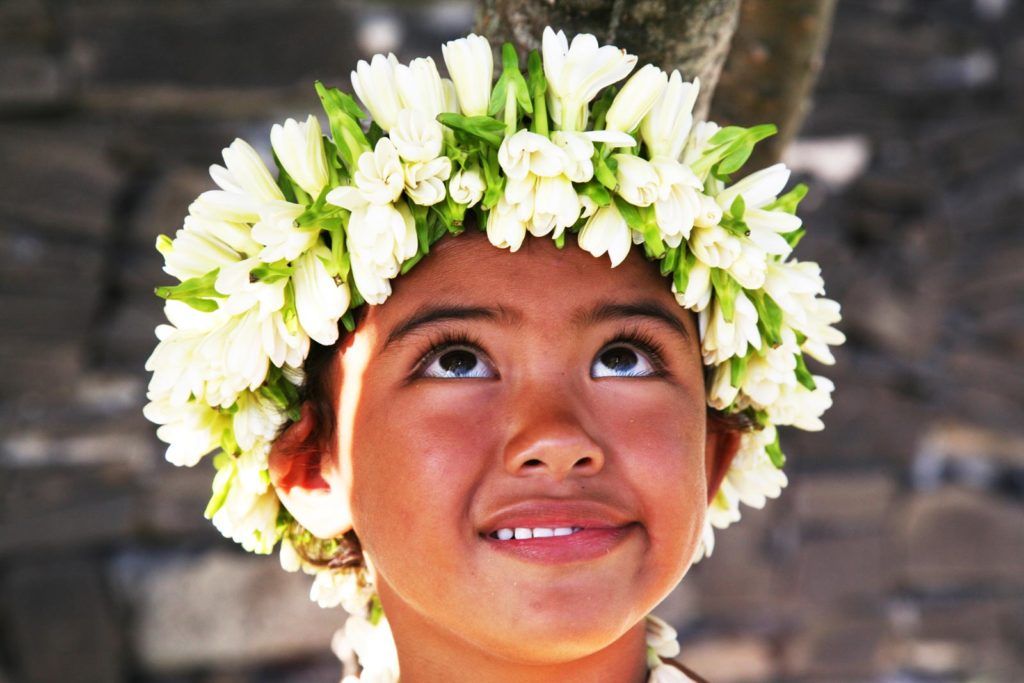 Niña con corona de flores en Polinesia
