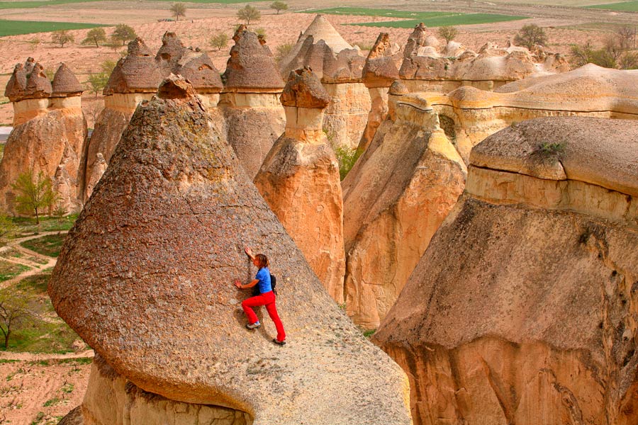 mujer escalando en las chimeneas de piedra de Capadocia