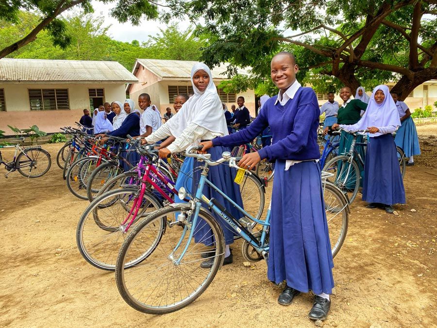 un grupo de niñas de Tanzania posa con una sonrisa con sus bicicletas