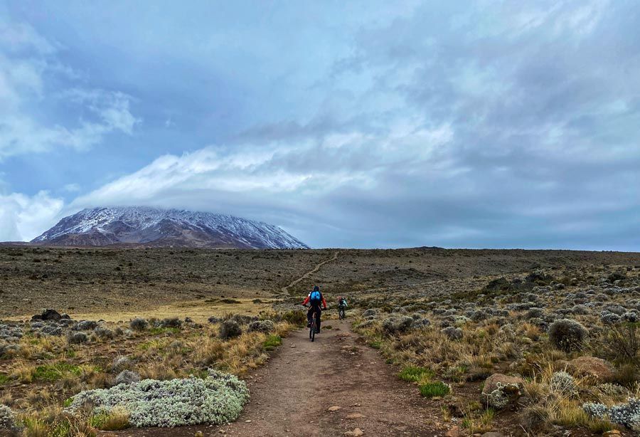 mujeres en bicicleta se dirigen al Kilimanjaro