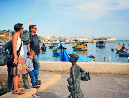 Una familia en un puerto de Malta junto a unas barcas
