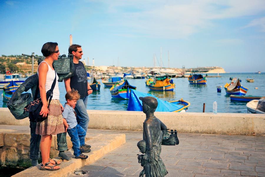 Una familia en un puerto de Malta junto a unas barcas