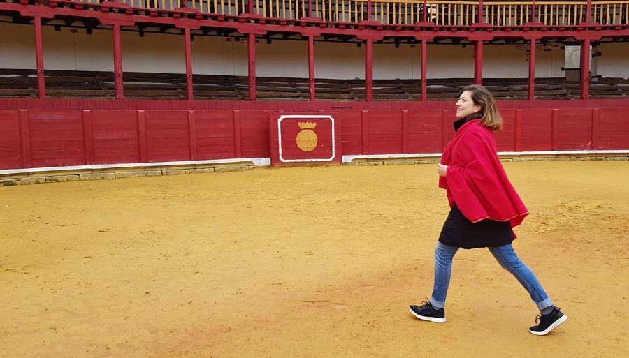 Una mujer con capa roja pasea por la plaza de toros de Toro.
