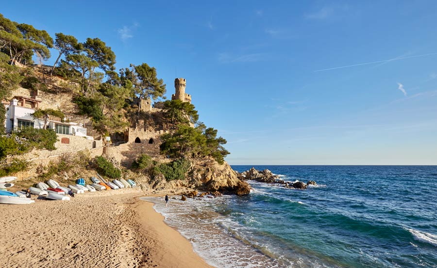 Playa de Sa Caleta con el castillo d'en Plaja al fondo. Visita esencial en un viaje a Lloret de Mar en un día