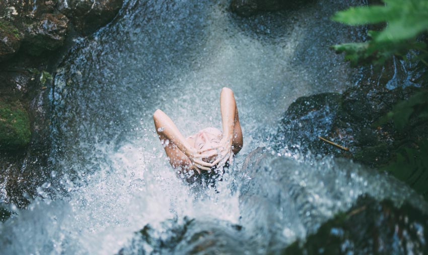 Mujer bajo el agua de una cascada