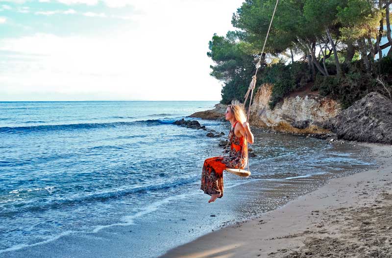 Mujer columpiándose en la playa S'Estañol en Ibiza