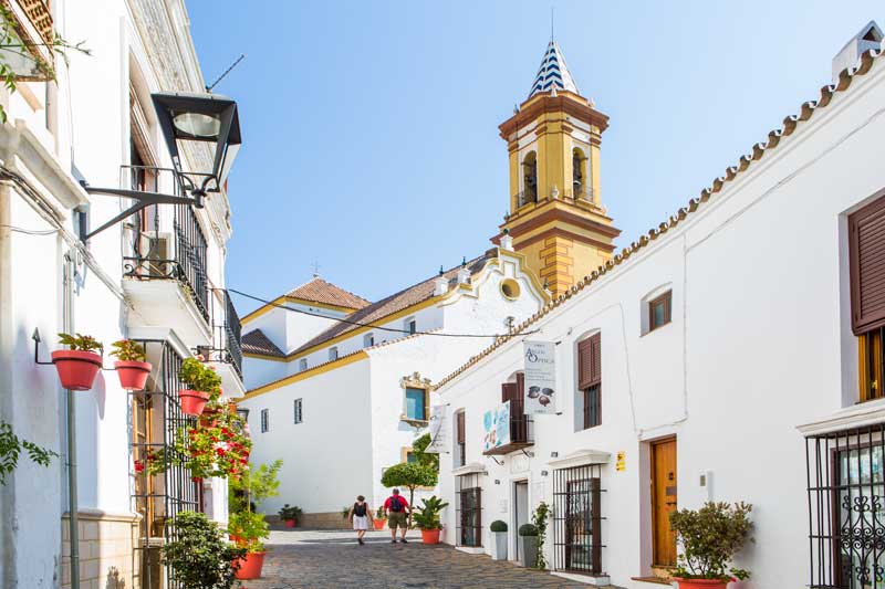 Calle y torre de la iglesia de los Remedios en Estepona