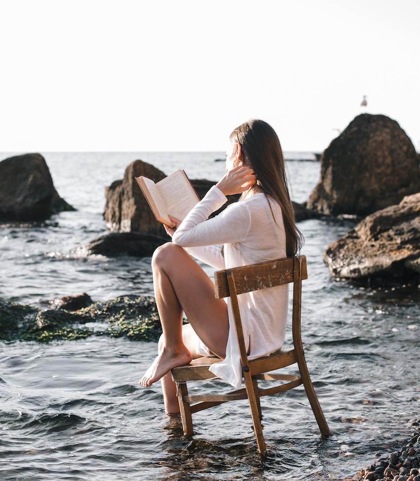 Mujer leyendo en la orilla del mar