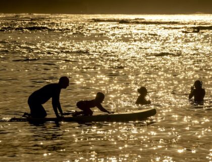 Playa de Las Canteras con niños bañándose al atardecer.